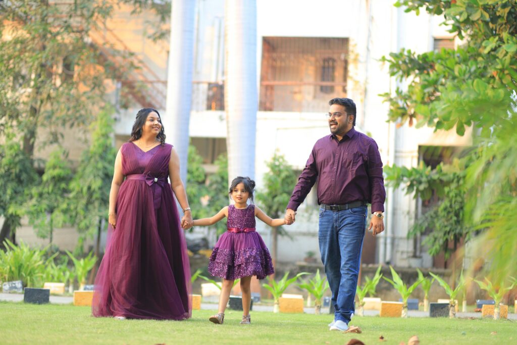 Charming family photoshoot outdoors with matching purple outfits and vibrant greenery.